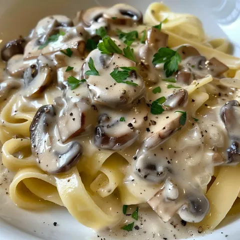 Tagliatelles recouvertes de sauce onctueuse aux champignons avec du persil dessus.