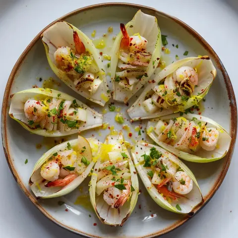 Des feuilles d'endives remplies de crevettes, morceaux de pommes et fines herbes, présentées sur un plateau.
