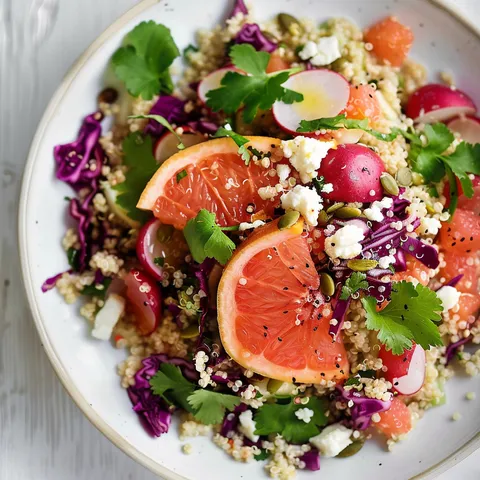 Une assiette appétissante de quinoa, chou rouge, radis et feta, rehaussée de pamplemousse et de graines croquantes.