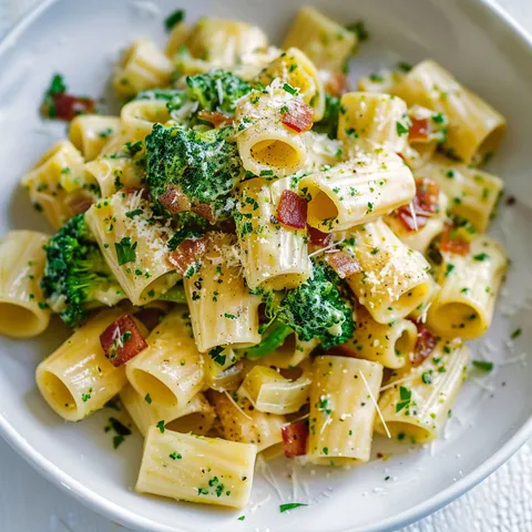 Assiette de pâtes carbonara avec brocolis et pancetta dorée.