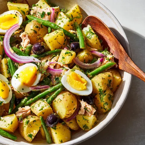 Un bol garni de pommes de terre, haricots verts, thon et œufs offre une assiette estivale.