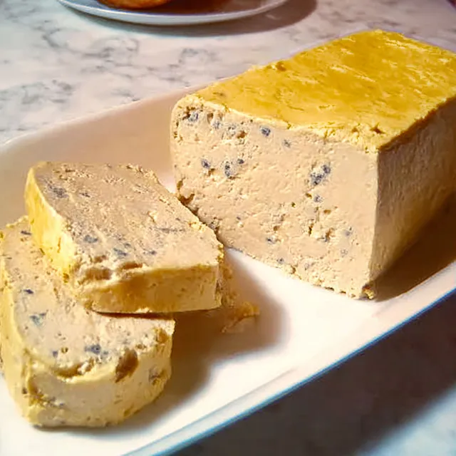 Une terrine fondante de foie gras de Joël Robuchon présentée sur une plaque élégante.