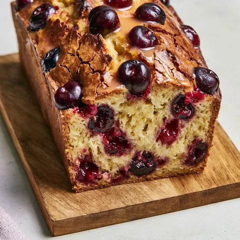 Un cake aux cerises et kirsch avec quelques cerises sur le dessus.