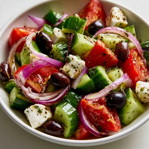 Un bol rempli de salade grecque avec tomates, concombres et feta.