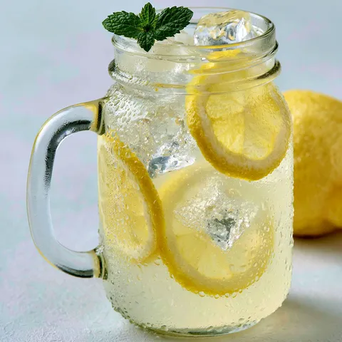 Un verre de citronnade rafraîchissante, décoré avec tranche de citron et herbes.