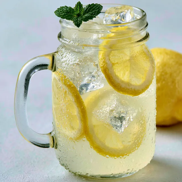 Un verre de citronnade rafraîchissante, décoré avec tranche de citron et herbes.