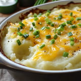 Pommes de terre écrasées nappées de crème fraîche et gratinées avec des oignons verts