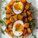 Une baguette garnie de légumes rôtis et œufs moelleux, accompagnée de roquette croquante, présentée sur un plat.