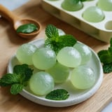 Petits bonbons verts faits main à la menthe, joliment posés sur un plateau en bois.