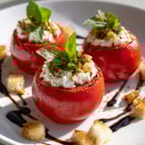 Tomates farcies à la stracciatella servies avec crostini et herbes fraîches.
