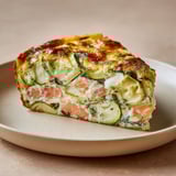 Un clafoutis courgettes et saumon, servi sur une assiette chic.