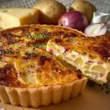 Vue appétissante d'une quiche raclette accompagnée de pommes de terre et d'oignons.