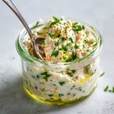 Une préparation au thon joliment présentée avec des herbes et une cuillère pour servir.