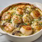 Savoureuses cassolettes aux Saint-Jacques dans une belle présentation en porcelaine.