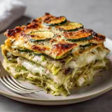 Un gratin doré de courgette et mozza sur un plat fumant.