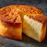 Un gâteau rond avec une part manquante, posé sur un plateau de granit.