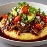 Assiette composée de polenta crémeuse et bœuf effiloché accompagné de légumes frais.