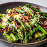 Des asperges sautées avec de la coppa et du fromage dans une poêle, prêtes à être dégustées.