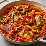 Un délicieux plat de poulet avec poivrons et tomates servi dans un bol.
