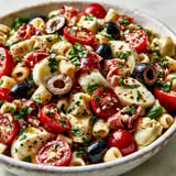 Un mélange coloré de pâtes, artichauts, jambon cru et mozzarella dans un bol.